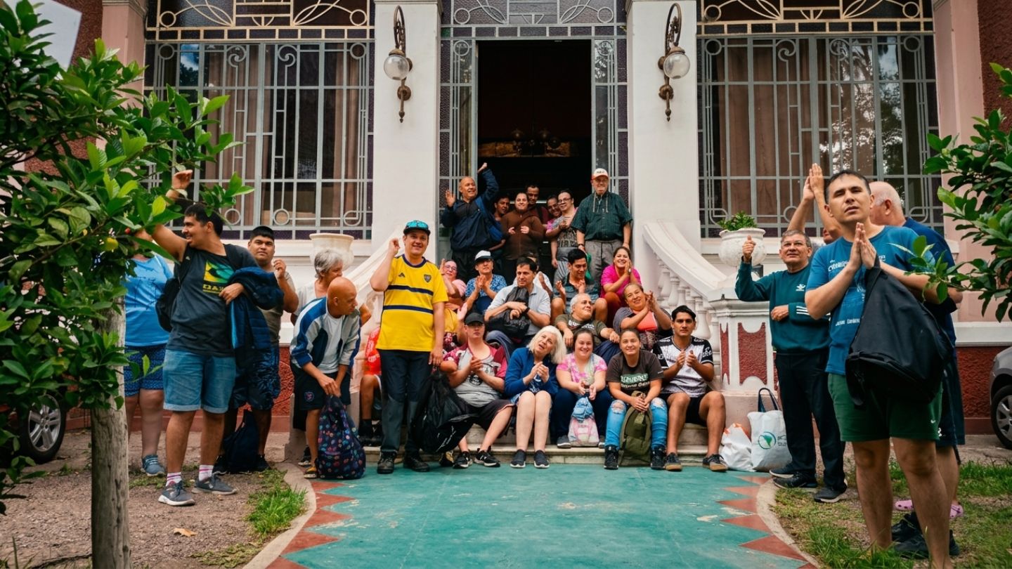 Foto grupal de alumnos y profesionales de IPSI en la entrada de una casa colonial, con expresiones de alegría y aplausos.