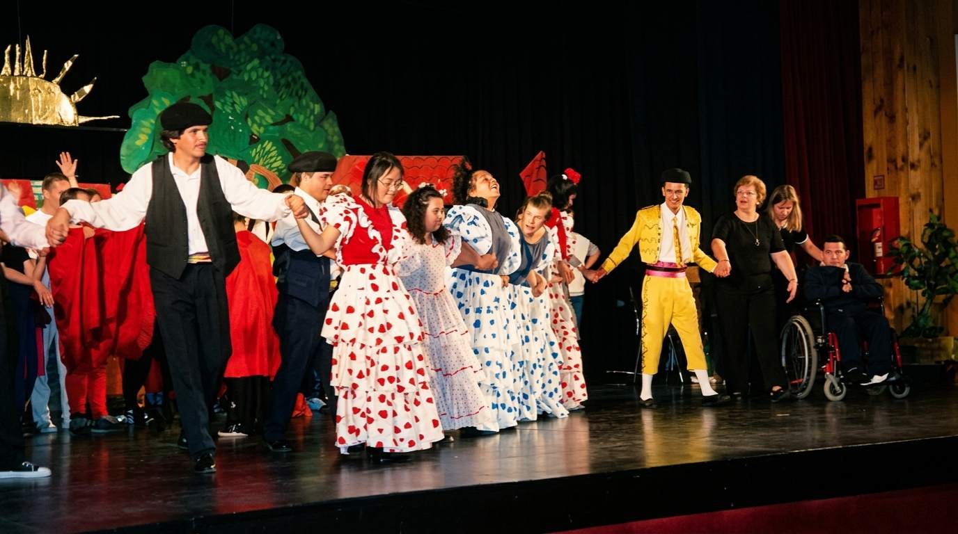 Archivo histórico IPSI: presentación de danza española en escenario, alumnos con vestidos de lunares blancos, rojos y azules y un bailarín vestido de torero.